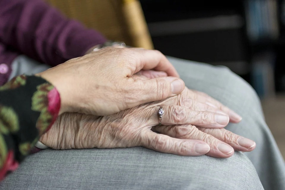 younger hand holding an elderly one